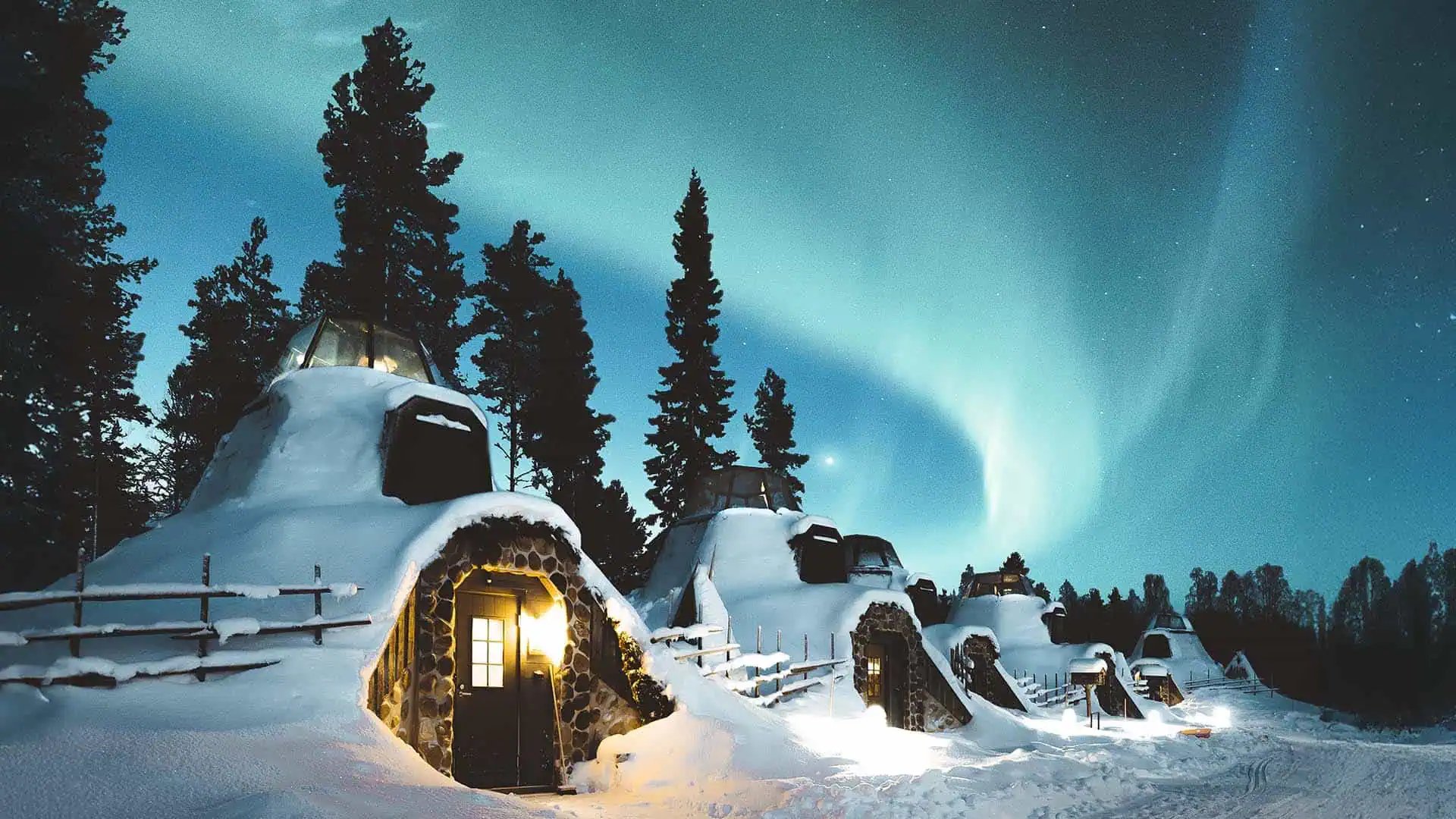 Apukka’s snow-covered Kammi suites under the northern lights