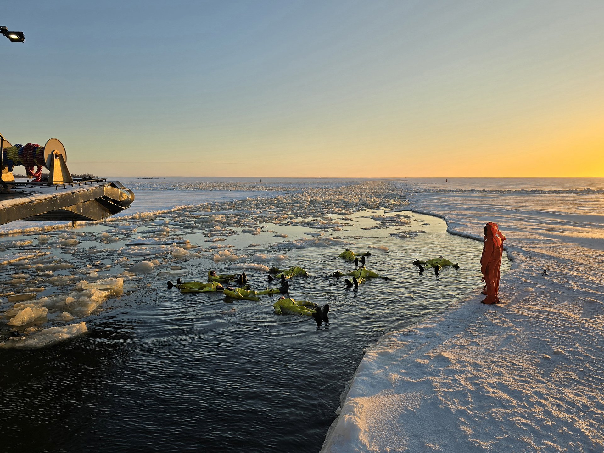 Passengers in survival suits floating among the ice beside Sampo at sunset